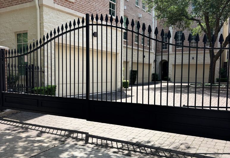 Custom ornamental steel driveway gate installed at a residential property in Austin, Texas featuring decorative ironwork and durable welded construction.