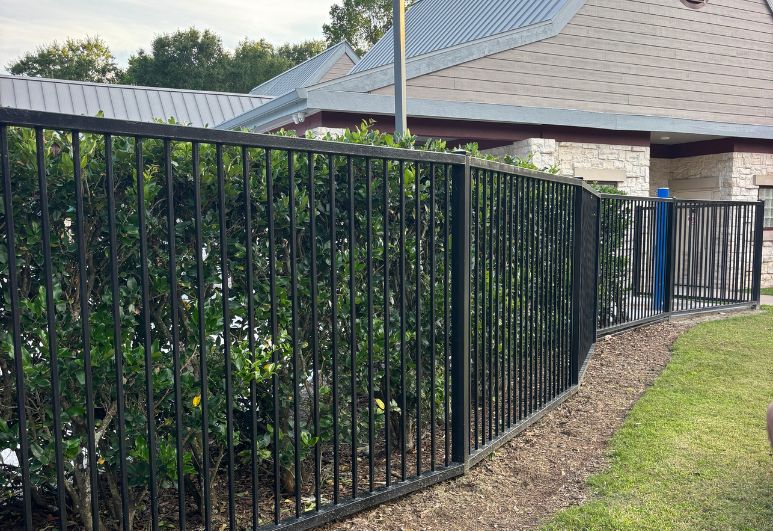 Commercial black steel pool security fence installed around a swimming pool facility in Austin, Texas with code-compliant safety fencing and secure access gates.