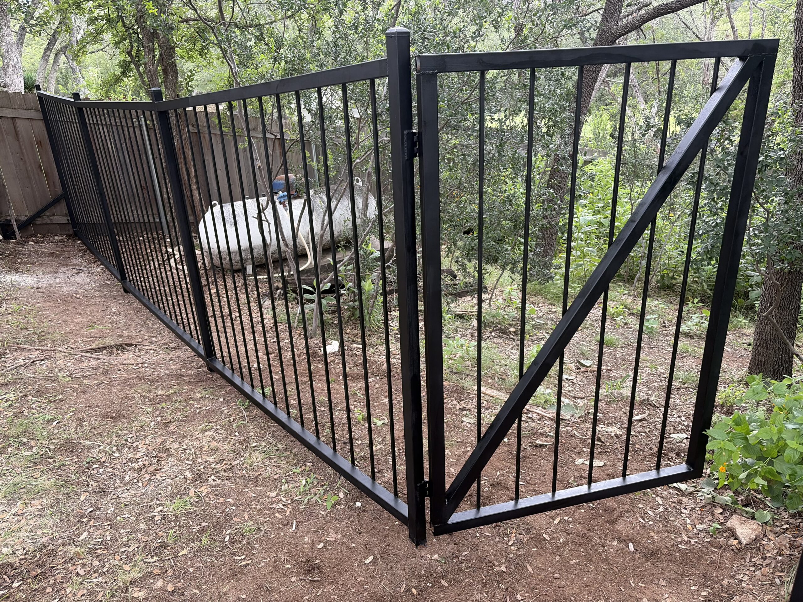 Steel driveway gate stuck open on an Austin Texas property needing repair